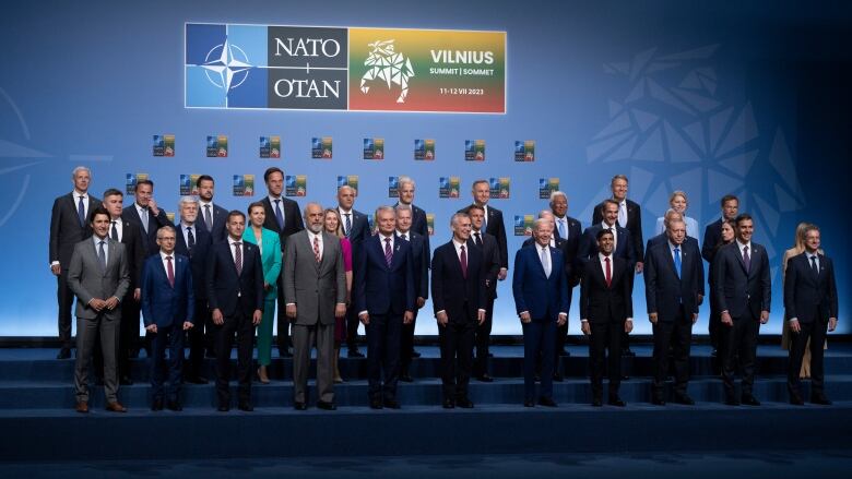 The heads of government of NATO countries pose for a photo on a stage in Lithuania. 