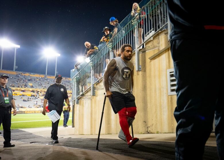 A football player uses crutches to leave a field after a game.