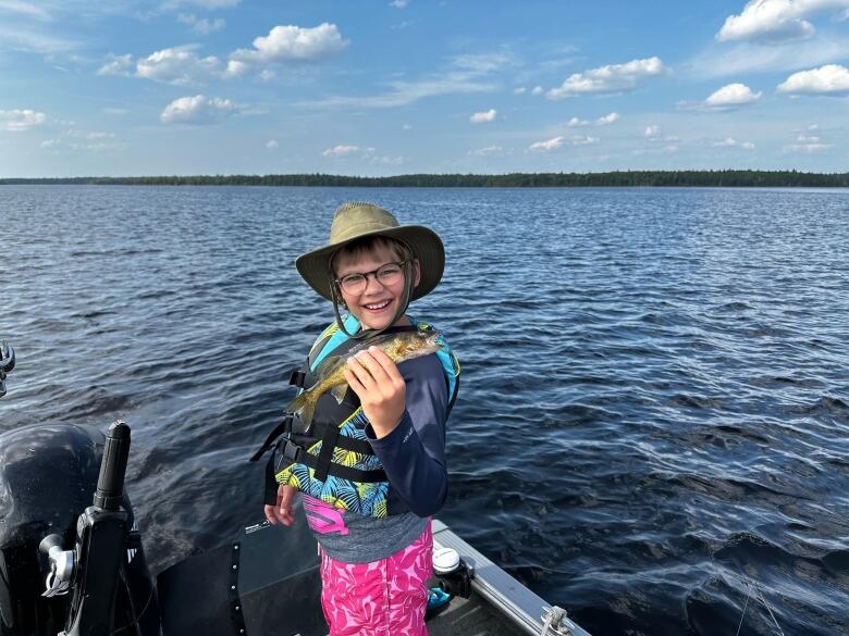 A young boy holds a fish