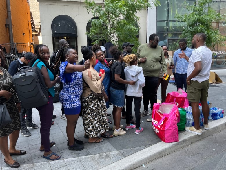 Asylum seekers line up as volunteers from the Black Coalition for AIDS Prevention hand out food, water and supplies.