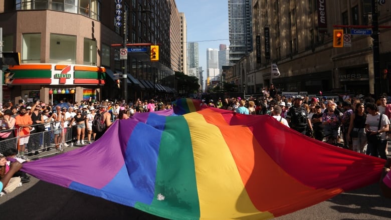 Participants carry a pride flag as they walk in the Toronto Pride Parade.