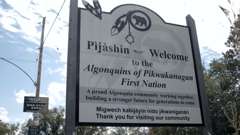 A welcome sign on the side of the road on a sunny day.