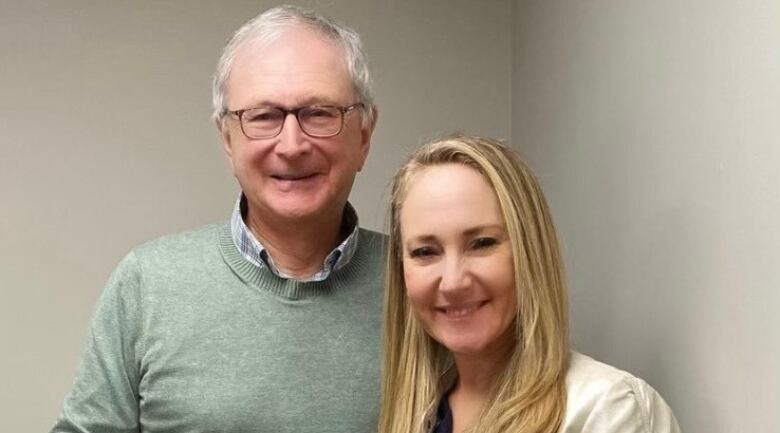 A man with grey hair and glasses posing with a woman with long blond hair