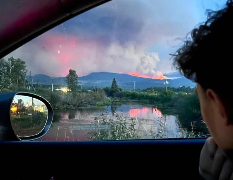 A person look at flames through a car window.