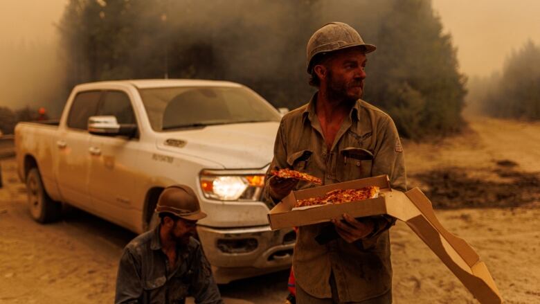 Firefighters from an Alaska smoke jumpers unit refuel with pizza on the fire line of a wildfire burning near a highway in northern British Columbia, Canada on July 11, 2023. 