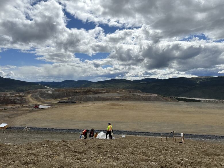 A small group of people is seen from afar, working on a large mine site.