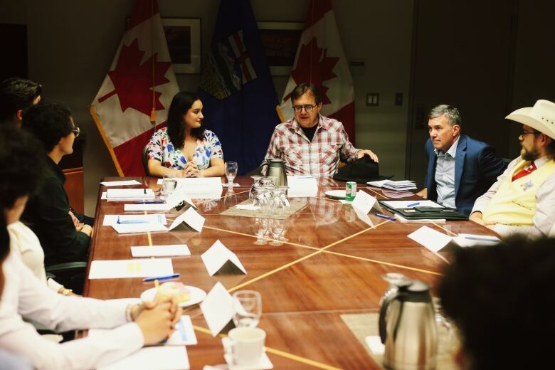 Cepeda Montufar listens to Minister Wilkinson speaking at a large wooden tables with papers and pens at each seat. Other students and political staff sit at the table. 