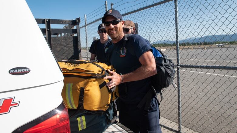 Several people unload firefighting gear from the back of a truck.