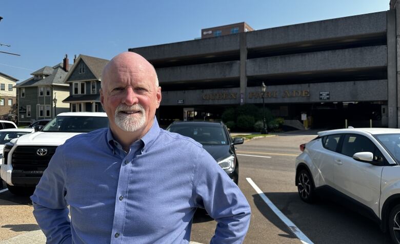 City councillor Norman Beck standing in front of the Queen Parkade in the sun. 