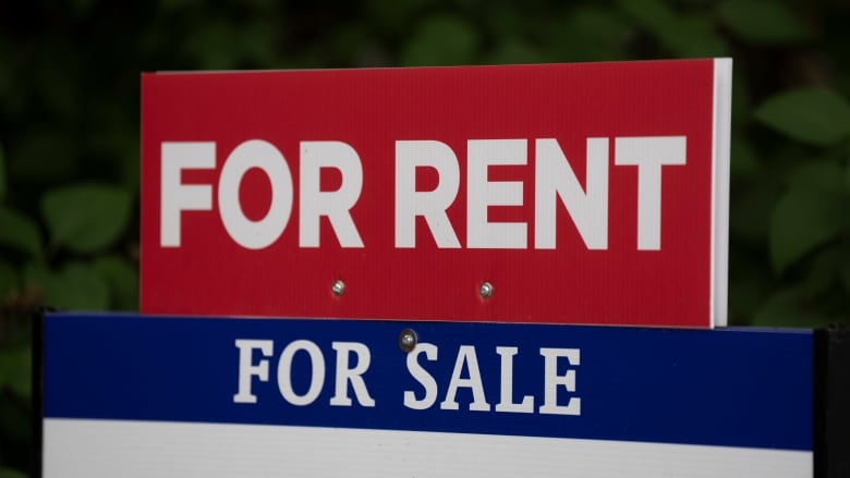 A real estate lawn sign displays a banner that reads 