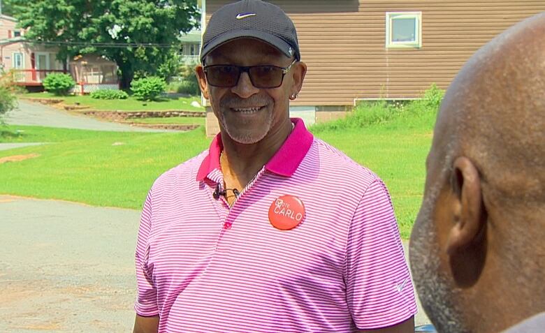 A man in glasses and a ballcap stands outside.