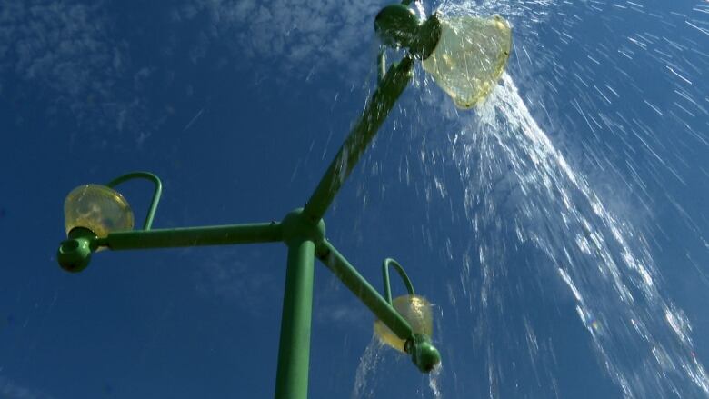 A green tower with three buckets of water spilling over. 