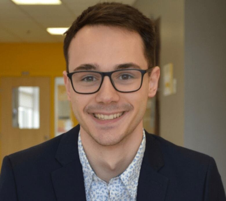 A young man smiles into the camera.