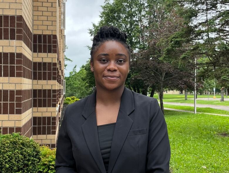 A woman in a dark suit is standing outside.