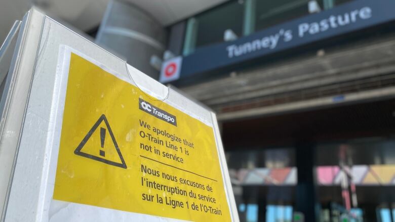 A yellow sign outside a train station says 'we apologize that O-Train Line 1 is not in service.'