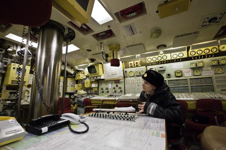 A Russian sailor sits in a submarine control room.