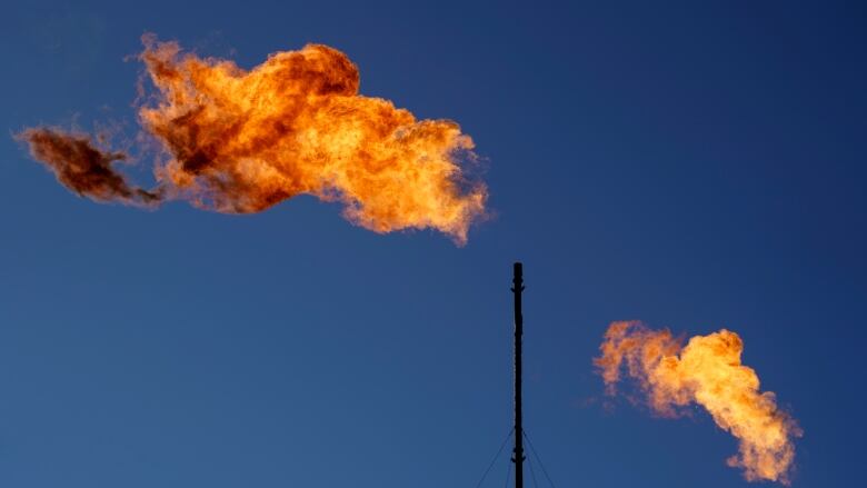 A series of pipes emit clouds of orange flame. The sky in the background is a deep blue. 