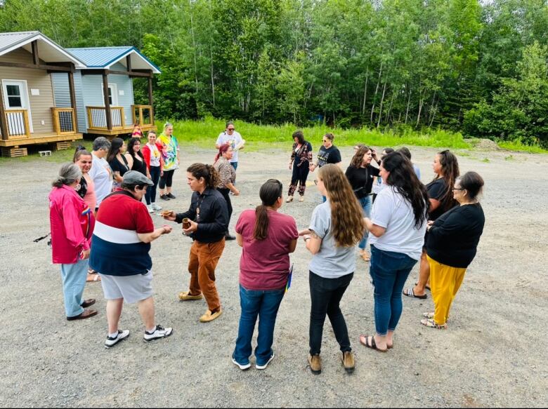 A group of people stand outside together in a circle.