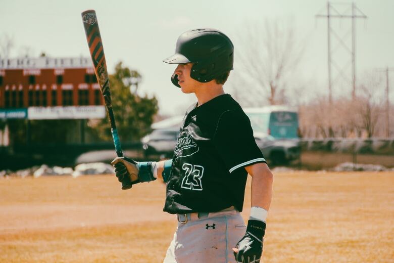 A baseball player wearing a helmet and gloves carrying a baseball bat. 