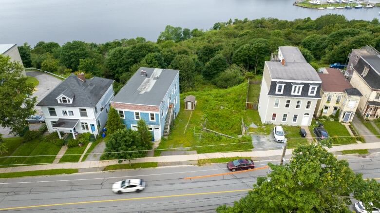 Aerial view of homes on a city street with cars driving by in front. 