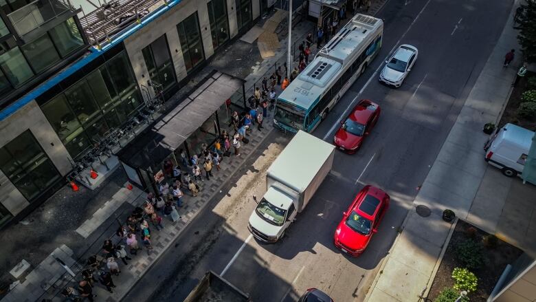 A bus stop from above, with a crowd of people waiting.