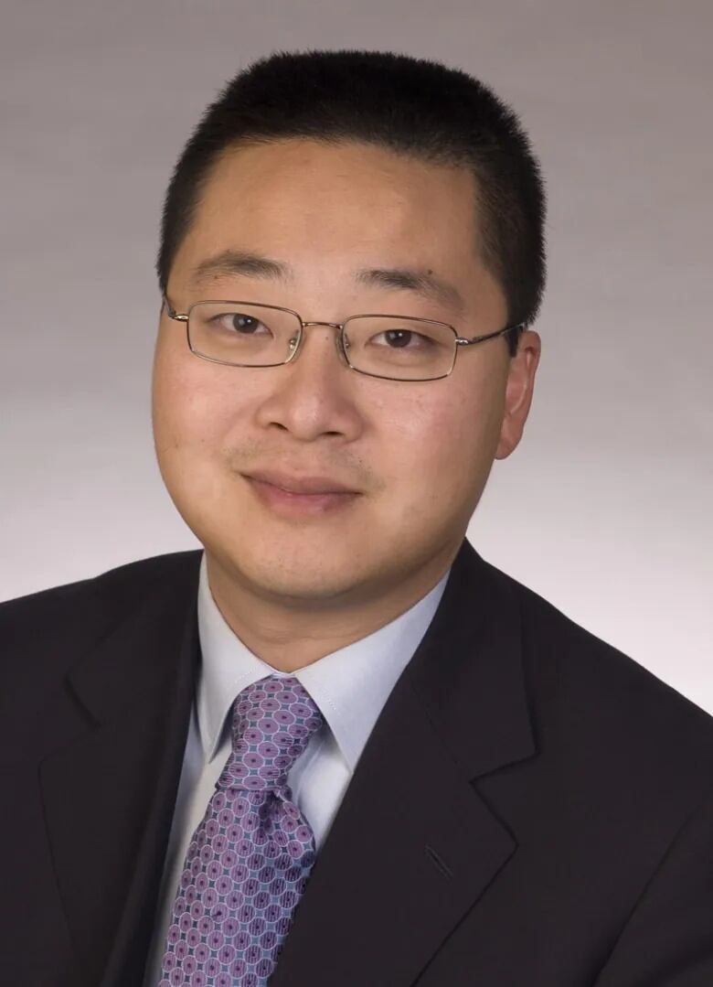 A man in a black suit and purple tie.