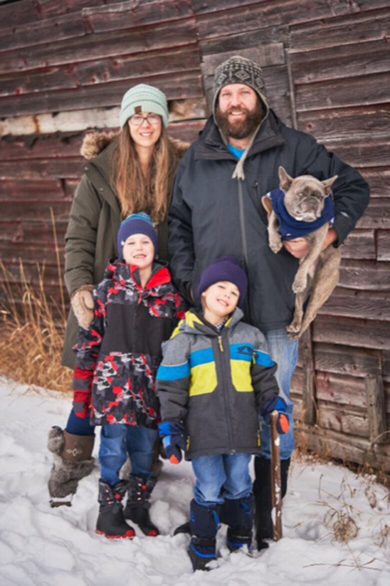 A woman stands alongside a man holding a dog and two boys. 