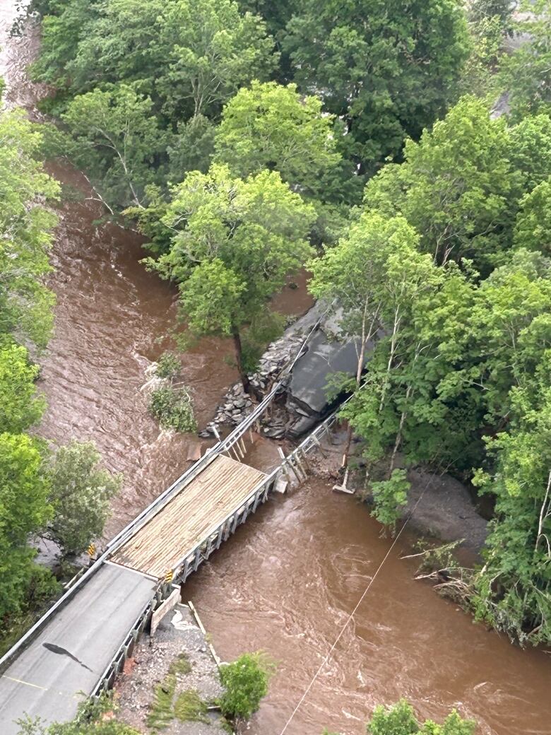 An aerial shot of a bridge where part of the road has washed away.