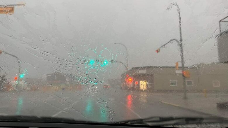 Looking through a windshield driving down a downtown street in heavy rain.