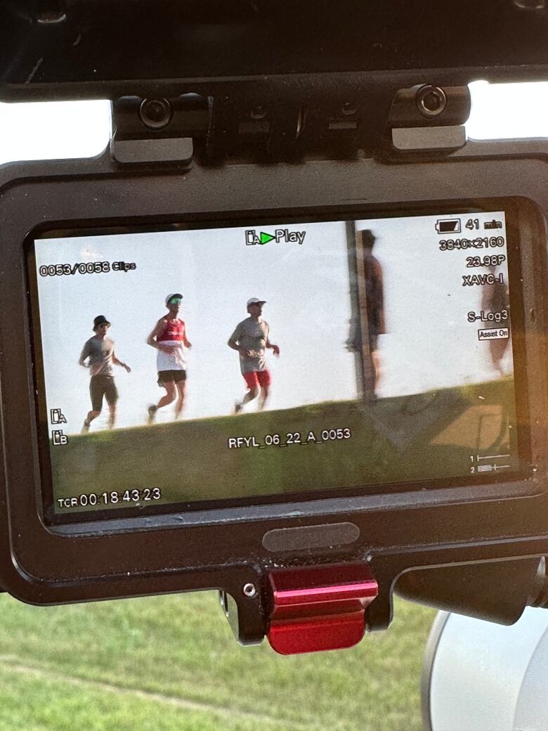 A group of runners jogging outdoors captured inside a digital camera screen.