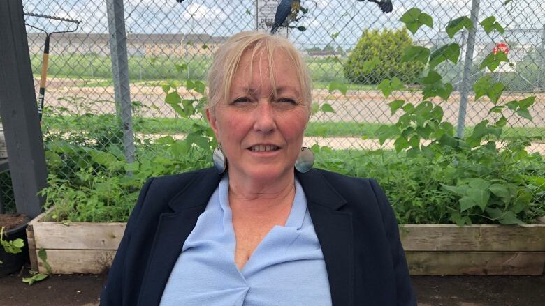 A woman sits in front of a raised vegetable bed.