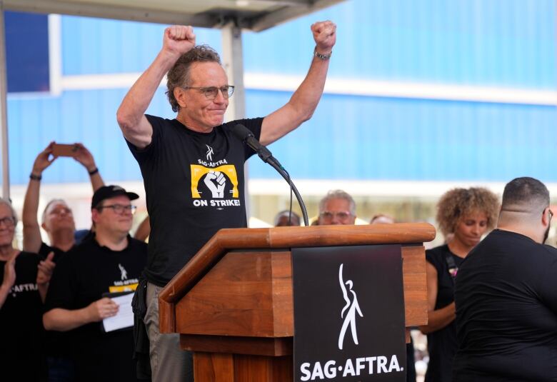 A man standing at a podium raises his fists in the air.