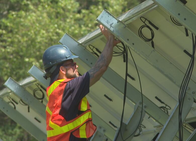 An electrician at work on the underside of a solar panel.