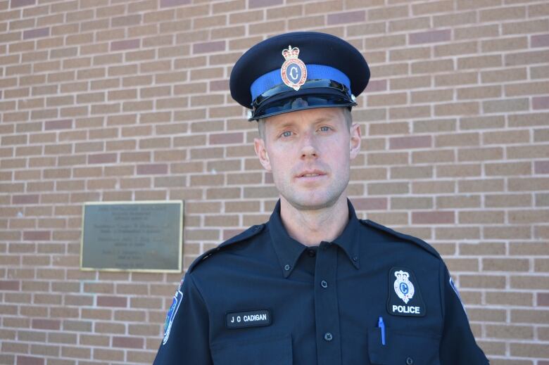 A man in police uniform against brick wall