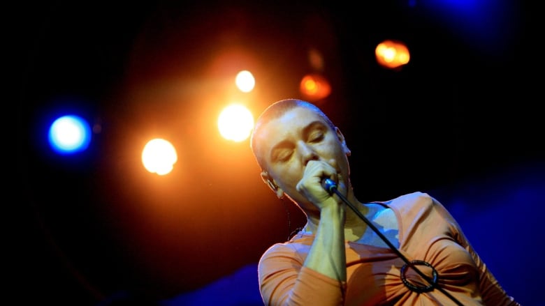 Colourful lights shine down on a woman as she sings onstage.