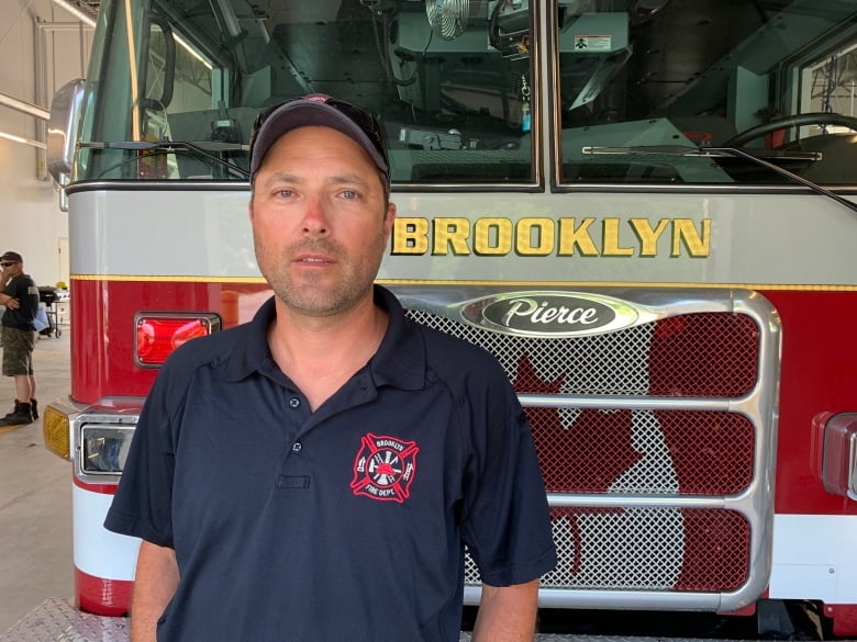 A man stands in front of a fire truck.