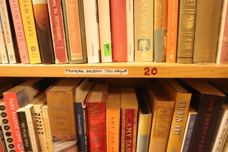 A filled bookcase with a sticker on it that says: Thoreau section this way. 