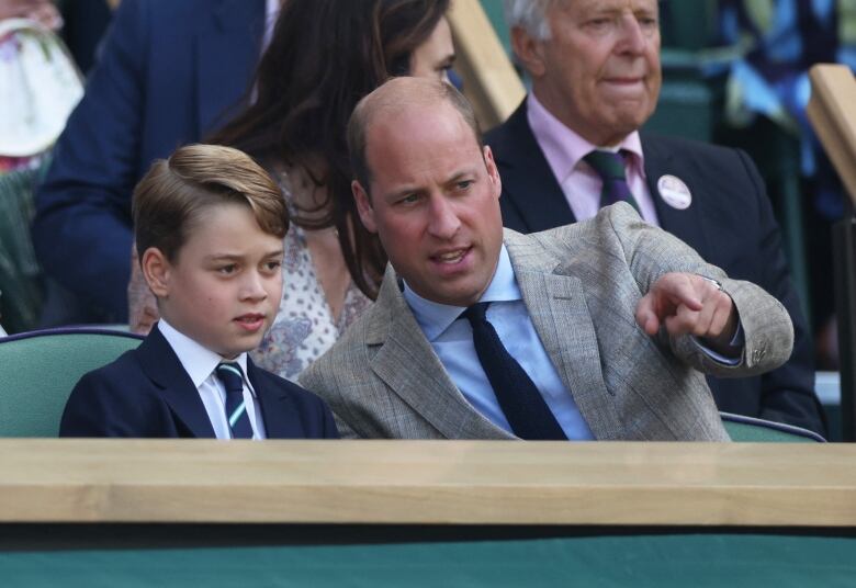 A child sits beside an adult who is pointing something out to them.