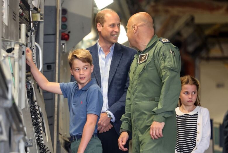 Two children and two adults stand inside a large military aircraft.