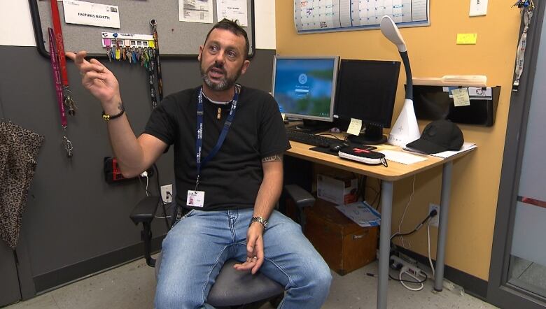 A man sitting in a chair with a naloxone kit on the desk beside him.