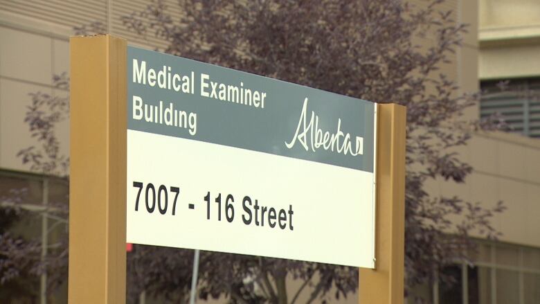 A sign is shown outside a grey building.