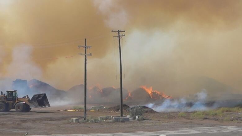 Piles of sawdust on fire with lots of smoke.