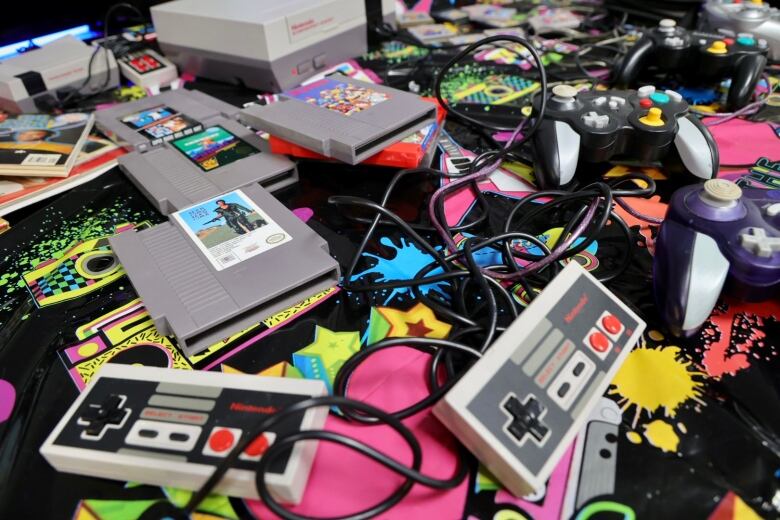 Old Nintendo controllers and games are strewn on a table.