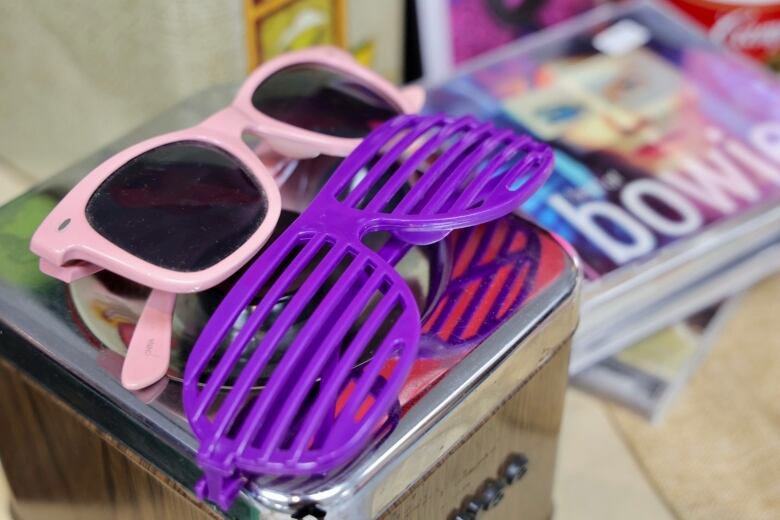 A pair of sunglasses in pink and shutter shades in purple.