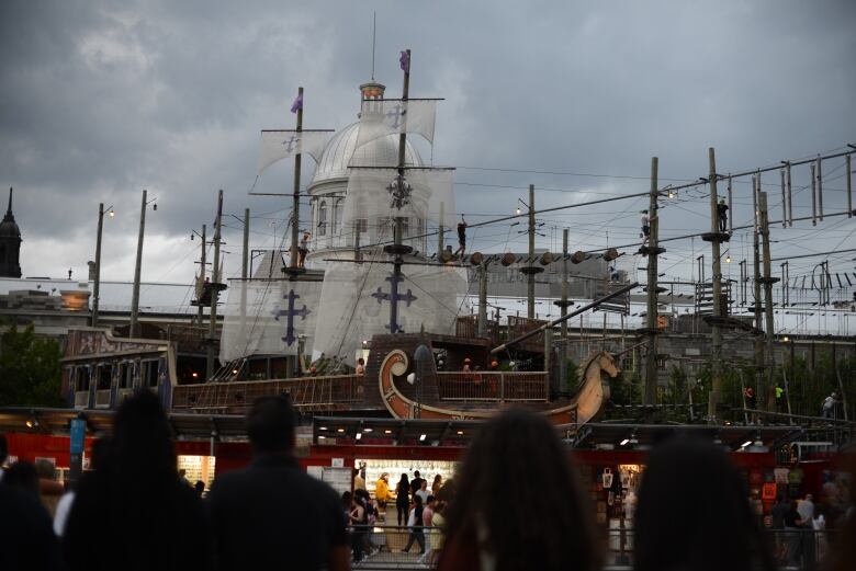 People balance across a rope course with shops nearby.