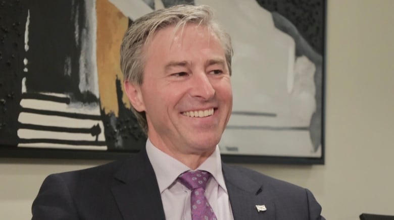 A man in a suite and tie smiles.