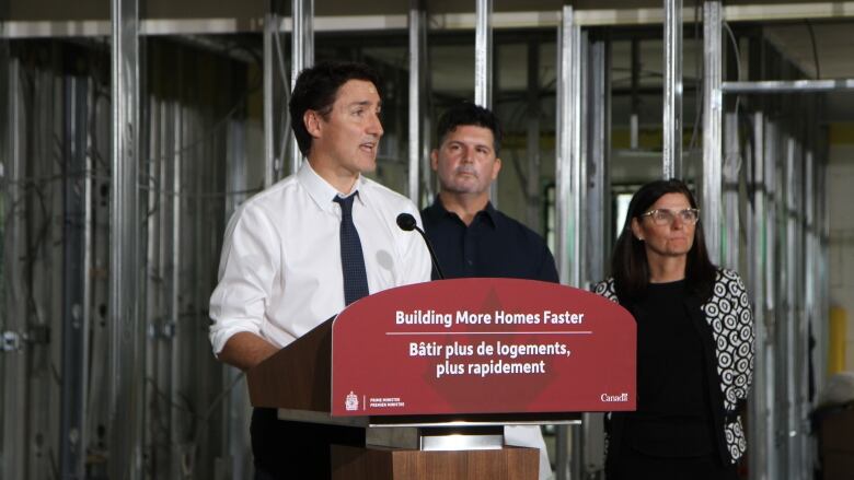 A man speaking on a podium. The podium has a sign that reads 