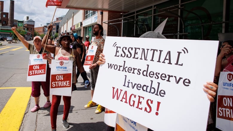 Metro workers hold signs outside one of the company's stores in Toronto.