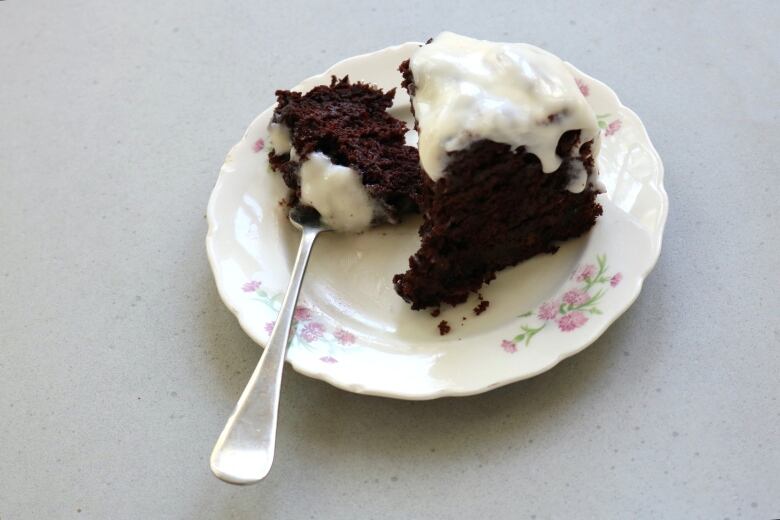 Chocolate cake with frosting on a white plate.