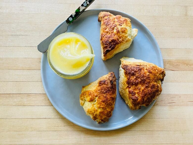 Lemon curd in a jar next to fried oatmeal on a plate.